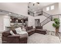 Open-concept living room with soaring ceilings, wrought iron staircase, and a seamless flow into the adjacent kitchen at 11127 E Tripoli Ave, Mesa, AZ 85212