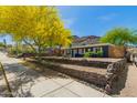 Charming home featuring attractive landscaping, a stone retaining wall, and a vibrant green tree against a mountain backdrop at 1527 E Sunnyslope Ln, Phoenix, AZ 85020