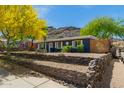 Charming home featuring attractive landscaping, a stone retaining wall, and lush green trees against a mountain backdrop at 1527 E Sunnyslope Ln, Phoenix, AZ 85020