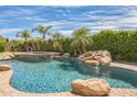 Backyard features a sparkling pool with a rock waterfall, palm trees, and lush greenery at 1805 W Dusty Wren Dr, Phoenix, AZ 85085