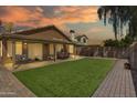 Spacious backyard featuring a covered patio, lush green lawn, and brick paver walkway, perfect for outdoor enjoyment at 18845 N 23Rd Pl, Phoenix, AZ 85024