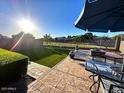 Backyard patio with outdoor seating, fire pit, grass, and sunny sky at 2070 E Saddlebrook Ct, Gilbert, AZ 85298