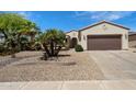 Inviting single-story home featuring a two-car garage and desert landscaping with mature palms at 20900 N Vista Trl, Surprise, AZ 85387
