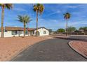 Wide, curved driveway leading to a well-maintained home with mature palm trees and attractive landscaping at 22312 W Hammond Dr, Buckeye, AZ 85326