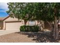 Well-maintained home exterior with a two-car garage, desert landscaping, and a mature shade tree at 30587 N Maple Chase Dr, San Tan Valley, AZ 85143