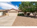 Traditional home exterior with tan stucco, a two-car garage, desert landscaping and a mature shade tree at 30587 N Maple Chase Dr, San Tan Valley, AZ 85143