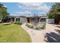 Quaint single-story home with a lush lawn, decorative landscaping, and distinctive awnings at 338 W Encanto Blvd, Phoenix, AZ 85003