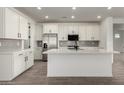 Stylish kitchen boasts white cabinets, stainless steel appliances, a spacious island with seating, and wood-look flooring at 4034 W Nora Dr, San Tan Valley, AZ 85144
