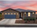 Charming single-story home with a blue garage door, stone accents, and desert landscaping at sunset at 41800 W Sonoran Trl, Maricopa, AZ 85138