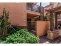 Charming exterior of home showcasing stucco, stone accents, private gate and lush greenery at 6940 E Cochise Rd # 1027, Paradise Valley, AZ 85253