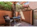 Private patio with brick flooring, stone pillar, wrought iron chairs, and a metal table at 6940 E Cochise Rd # 1027, Paradise Valley, AZ 85253
