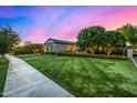 Well-manicured front lawn and garden of a charming home, illuminated against a twilight sky at 17690 E Bronco Dr, Queen Creek, AZ 85142