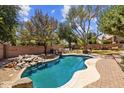 Backyard pool featuring mature trees, a stone waterfall, and an outdoor dining set for entertaining at 1943 E Drake Dr, Tempe, AZ 85283