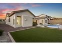 Well-maintained backyard featuring a pool, artificial grass, and desert landscaping under a colorful sky at 3551 W Hidden Mountain Ln, Anthem, AZ 85086