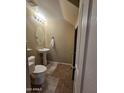 Compact bathroom featuring a pedestal sink, tiled floor, and a stylish oval mirror at 44328 W Knauss Dr, Maricopa, AZ 85138