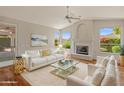Bright living room with a white sofa, fireplace, and windows offering a view of the garden at 5936 W Via Montoya Dr, Glendale, AZ 85310