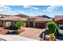 Charming single-story home with a three-car garage, tile roof, desert landscaping, and a brick driveway at 10345 W Fetlock Trl, Peoria, AZ 85383