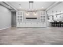 Open-concept living room with modern light fixture, stylish built-ins, and tile flooring at 10345 W Fetlock Trl, Peoria, AZ 85383