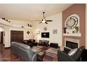 Cozy living room with a fireplace, ceiling fan, and comfortable seating arrangement at 10974 S Dreamy Dr, Goodyear, AZ 85338