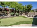 Landscaped backyard featuring a putting green, fire pit, basketball hoop and mature trees at 11088 E Acacia Dr, Scottsdale, AZ 85255