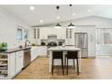 A well-lit kitchen features stainless steel appliances, white cabinets, a kitchen island, and hardwood floors at 15629 N 63Rd Pl, Scottsdale, AZ 85254