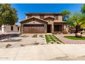 Inviting two-story home featuring a lush front yard, stone details, and a convenient two-car garage at 16102 W Redfield Rd, Surprise, AZ 85379
