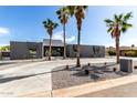 Striking modern home with a gray exterior, desert landscaping, and a curved concrete driveway lined with mature palm trees at 5111 E Cortez Dr, Scottsdale, AZ 85254