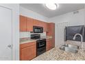 Kitchen featuring granite countertops, wood cabinets, and black appliances at 5302 E Van Buren St # 2015, Phoenix, AZ 85008