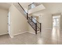 Bright entryway featuring tile floors and an open staircase with dark wood railings at 121 W Hackberry Dr, Chandler, AZ 85248