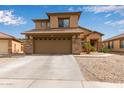 Two-story home with a two car garage, stone accents, desert landscaping, and neutral color palette at 15429 W Statler Cir, Surprise, AZ 85374