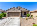 Inviting single-story home boasts a spacious driveway, desert landscaping, and a warm exterior at 18008 W Tina Ln, Surprise, AZ 85387