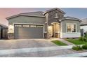 Charming single-story home featuring stone accents, a well-manicured lawn, and a spacious gray garage door at 18358 W Christy Dr, Surprise, AZ 85388