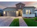 Beautiful home exterior with stone accents, lush landscaping, and a paver driveway leading to the garage and entryway at 18358 W Christy Dr, Surprise, AZ 85388