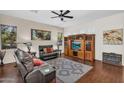 Well-lit living room with hardwood floors, a ceiling fan, comfortable seating, and entertainment center at 2000 W Periwinkle Way, Chandler, AZ 85248