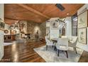 Bright dining area with stone fireplace, wood ceilings, and modern lighting fixture at 41590 N 108Th St, Scottsdale, AZ 85262