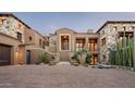 Stately desert home with stone accents, a paver driveway, and lush xeriscaping for elegant curb appeal at 42155 N 97Th Way, Scottsdale, AZ 85262