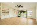 Well-lit living room featuring wood floors, modern ceiling fan, built-in shelving, and backyard access at 5402 E Michelle Dr, Scottsdale, AZ 85254