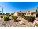 Inviting front exterior featuring manicured landscaping, stone accents, and a well-maintained lawn at 7002 E Exmoor Dr, Mesa, AZ 85208