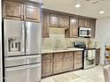 Well-lit kitchen with stainless steel appliances, mosaic tile backsplash, and ample dark wood cabinetry at 7943 W Mariposa Dr, Phoenix, AZ 85033