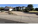 Exterior shot of a single-Gathering home with lush landscaping, front yard, and curved driveway at 10205 E Corrine Dr, Scottsdale, AZ 85260