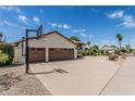 View of the home's three-car garage with basketball hoop and expansive driveway and desert landscaping at 10205 E Corrine Dr, Scottsdale, AZ 85260