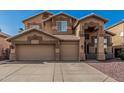 Front of a two-story home featuring a three-car garage, neutral color scheme, desert landscaping, and a concrete driveway at 13750 W Roanoke Ave, Goodyear, AZ 85395