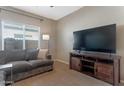Comfortable living room with carpet, large TV, and window providing natural light at 18023 W Statler St, Surprise, AZ 85388
