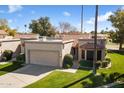 Charming single-story home features a two-car garage and well-maintained front yard with lush green grass at 19205 N 93Rd Ave, Peoria, AZ 85382