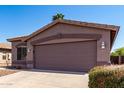 Single story house with a 2 car garage, desert landscaping and a clear blue sky at 43711 W Elm Dr, Maricopa, AZ 85138