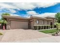Spacious three-car garage with brick paver driveway, landscaping, and stone detailing on the home's exterior at 5291 S Bradshaw Pl, Chandler, AZ 85249