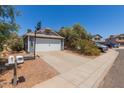 Charming single-story home with a gray exterior, a two-car garage, and a basketball hoop in the driveway at 6320 W Mercer Ln, Glendale, AZ 85304