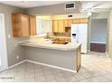 Bright kitchen with wood cabinets, tiled countertops, and a modern refrigerator at 814 S 80Th St, Mesa, AZ 85208