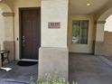 Cozy covered front porch featuring a sturdy front door, textured walls, and neighborhood views through the adjacent window at 9137 W Coolbrook Ave, Peoria, AZ 85382