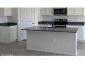 Modern kitchen featuring an island with a sink and dark countertop paired with white cabinets at 1360 W Hess Ave, Coolidge, AZ 85128